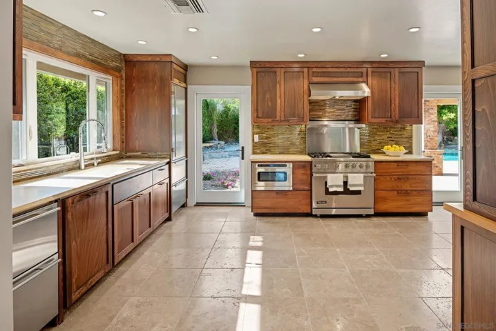 Under-counter fridge and freezer drawers are on the left.  Next to that is a Bosch dishwasher with a wood panel front.  SubZero built-in fridge/freezer is at the other end of the kitchen counter.