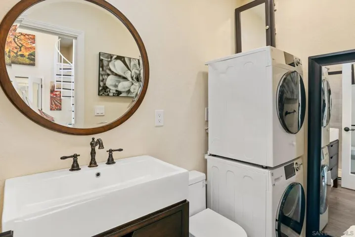 The Guest House bathroom has a shower, sink, toilet,  and stacked laundry appliances.