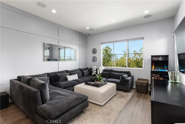 Spacious living room features a bright, open layout with abundant natural light, decorative wall finish and vinyl wood flooring.