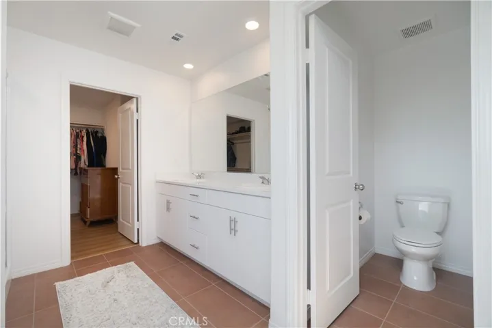 Primary bathroom with 2 sinks, privacy toilet door, walk-in closet, shower and glam bar