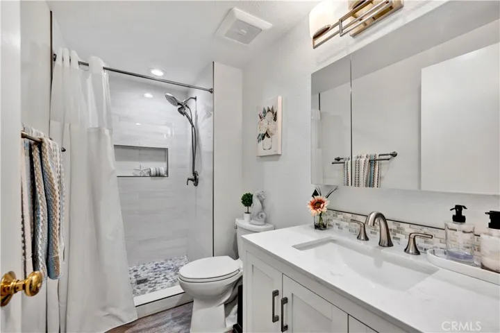 Primary Suite has walk in shower - newer vanities, Quartz countertops, wood-look vinyl flooring, and updated mirrors and fixtures