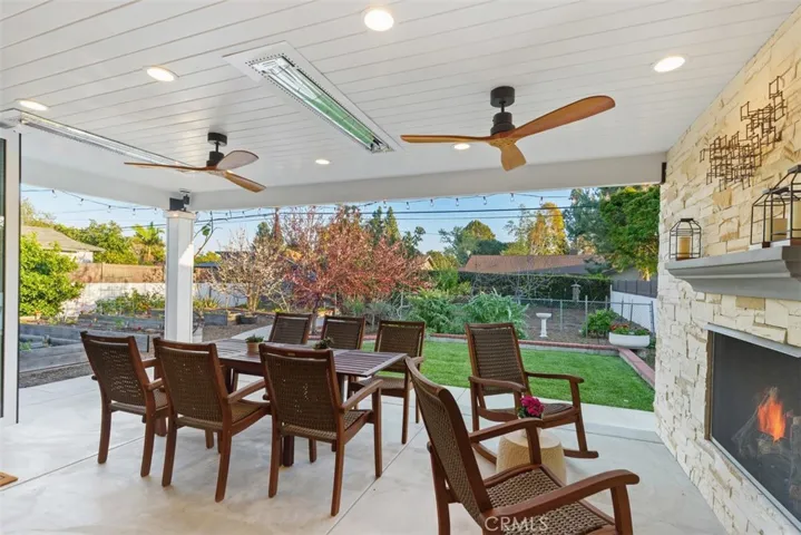 Fully covered patio with electric fireplace, heaters, ceiling fans, lighting, custom masonry and mantle. Panoramic doors open all the way out creating an inviting indoor-outdoor living space.