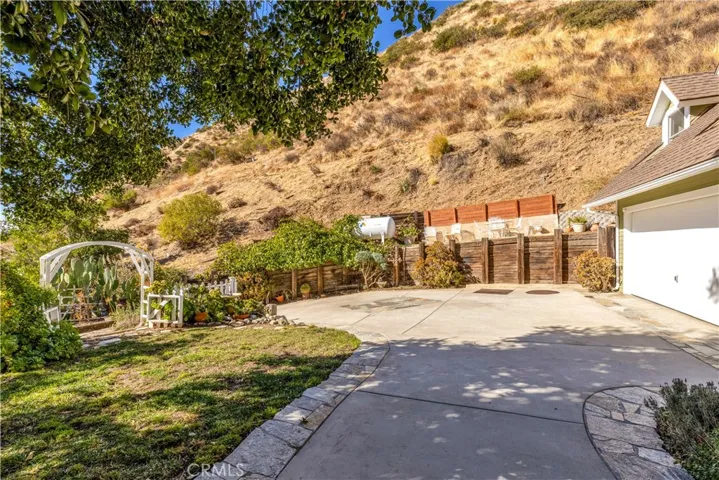 Front of the house coming from the view will deck with grapes growing down the wall on the driveway