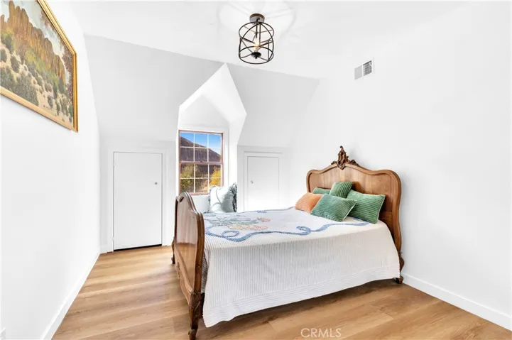 A quaint bedroom with window seating that provides storage as well as the two tiny closets next to the window and the main mirrored closet