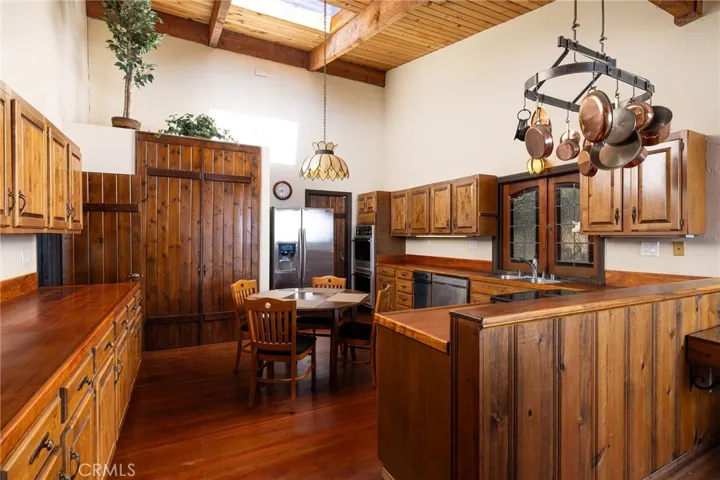 Kitchen features tall ceiling with skylight, ample cabinetry space, walk-in pantry, and direct access to the 1-car garage.