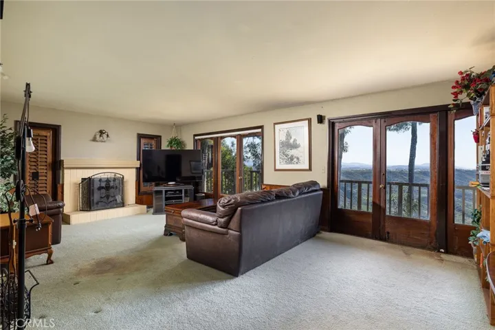 Mid-level family room is situated between the primary suite and the secondary bedrooms with a cozy fireplace, french doors, and view deck.