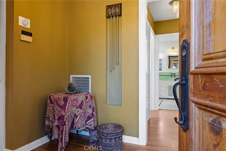 Front Entry Foyer: custom wood door detail, original hardwood flooring, 3-chime doorbell, wide sculpted mouldings run throughout the house, 3-toned paint schemes throughout the house, the entire interior is freshly painted, hallway to large bathroom and two bedrooms, period light fixture, large entry closet just out of view at left.

