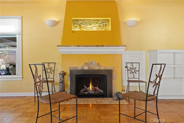 Formal Living room: fireplace detail, Mission style design, full masonry fireplace, original tiled hearth, front piece and mantle, fresco of the Santa Barbara Mission, remote controlled enclosed gas log insert, rear loading through-the-wall wood storage locker to right of fireplace.

