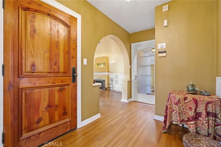 Front Entry Foyer: custom wood door, period hardware, original hardwood flooring, archway to formal living room, glass door to enclosed breezeway to 3rd bedroom and laundry room, large entry closet out of view to left of glass door.

