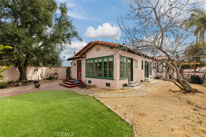Back Yard: red door to kitchen, green single door to Sun Room, green double doors to North Bedroom, gate to pergola and pool yard at rear, producing fig tree at right.

