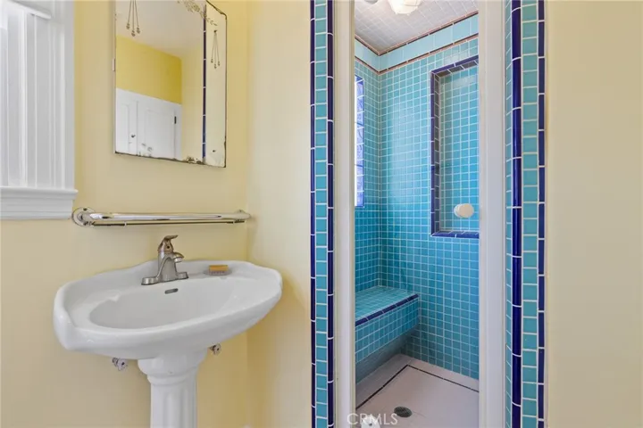 Attached Bathroom: pedestal sink, shower detail with custom vintagesque full-tile shower with seat & glass block insert, newer glass shower door.


