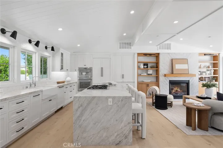 At the heart of the home, the chef’s kitchen features bespoke shaker cabinetry, premium Thermador appliances, and a large waterfall stone island that anchors the space while flowing seamlessly into the light-filled living and dining areas.