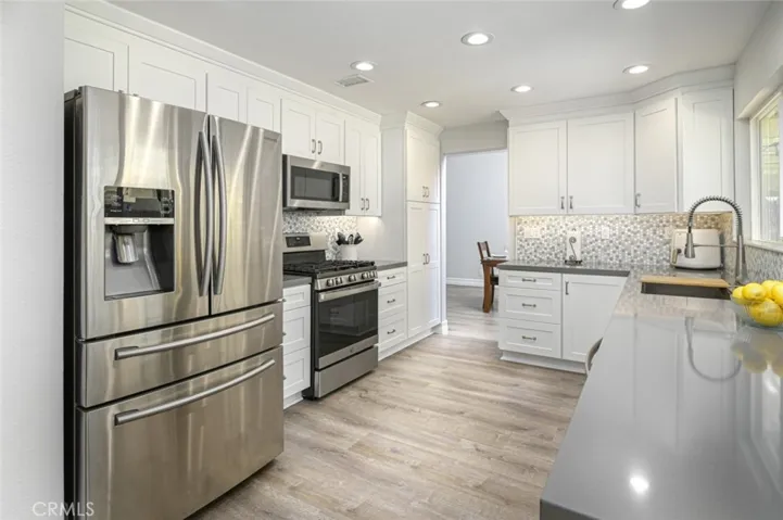 Remodeled kitchen has recessed lighting, quartz countertops, and a gorgeous detailed backsplash