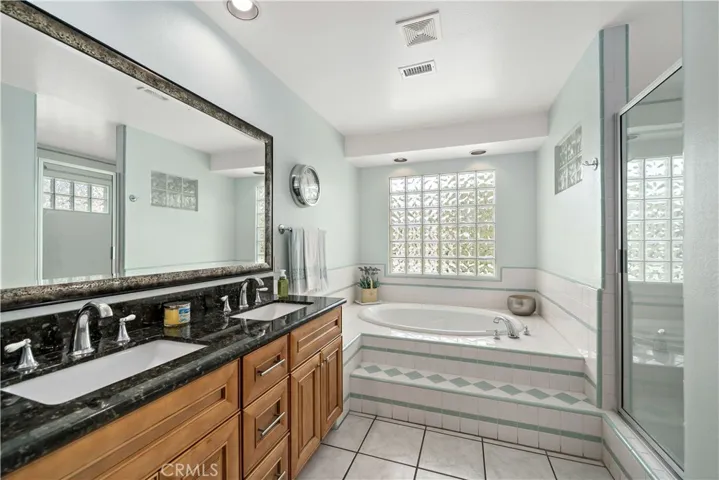 Primary bathroom w dual sinks and separate tub and walk-in shower.