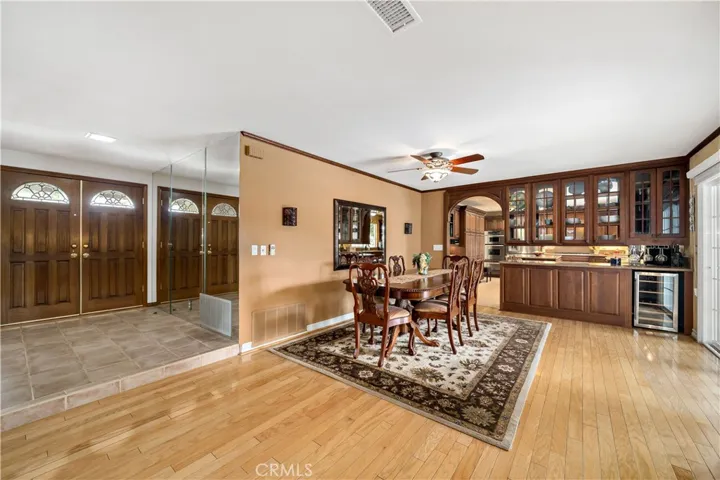 Expansive dining area w see thru cabinetry, custom paint, ceiling fan/light fixture and wine fridge.