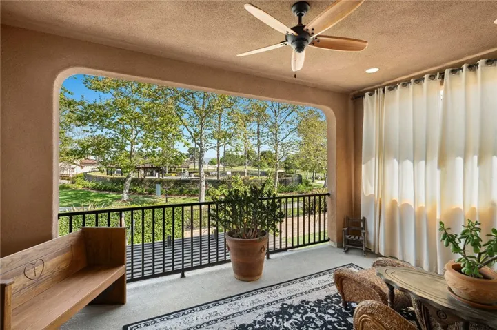 Spacious covered deck off of the primary suite with forever views of the golf course and mature foliage