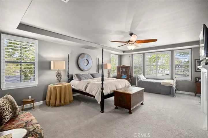 Oversized primary suite with tray ceilings, plantation shutters and attached balcony