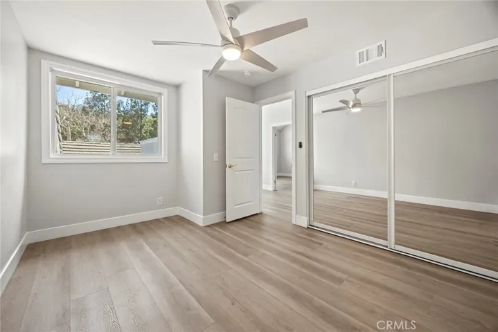 ONE GUEST BEDROOM WITH CEILING FAN AND MIRRORED CLOSET DOORS.