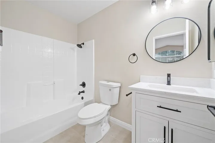 The ensuite bathroom features a resurfaced shower and a white shaker vanity.


