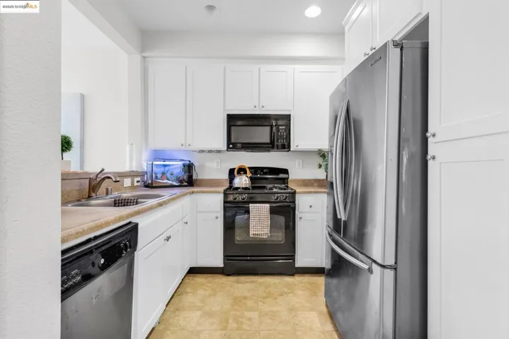 Kitchen with black appliances, white cabinets, light countertops, and recessed lighting