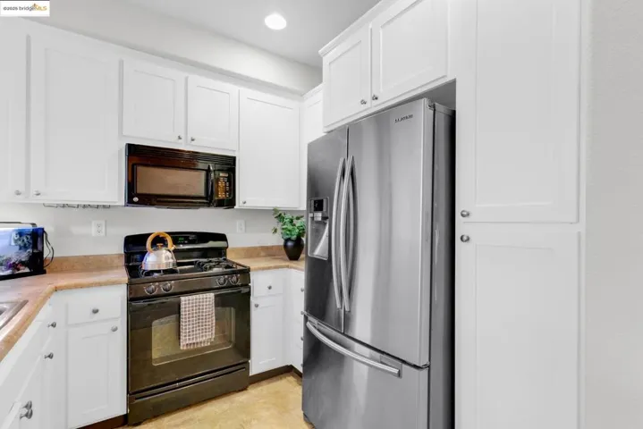 Kitchen with black appliances, white cabinetry, light countertops, and recessed lighting