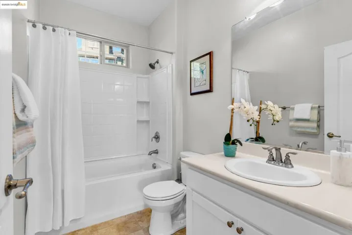 Bathroom with shower / bathtub combination with curtain, vanity, and light tile patterned floors