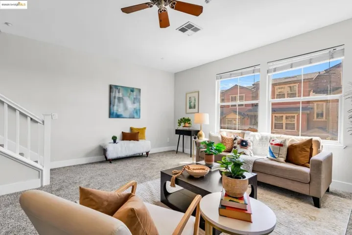 Living area featuring carpet floors, stairs, and ceiling fan