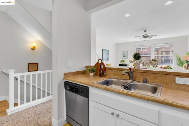 Kitchen with stainless steel dishwasher, white cabinets, light countertops, ceiling fan, and recessed lighting