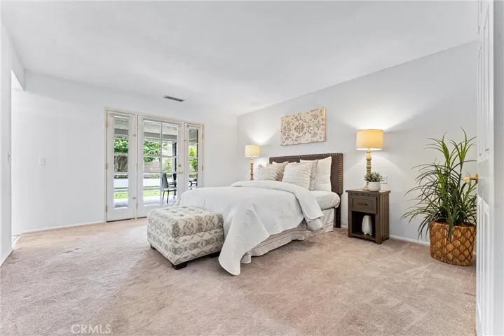 Heading in to the spacious primary bedroom.  The French door leads you to the covered patio.