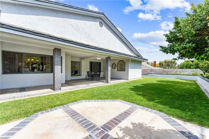 This backyard shot is from the raised pad and a look to the kitchen windows, the patio and two custom windows of the main suite bathroom.