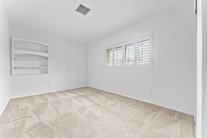 At the end of the hallway is the first of three secondary bedrooms.  Built in shelves and plantation shutters compliment the room.