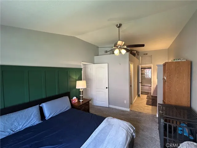 Primary large bedroom with  walk in closet . Ceiling fan, plenty of natural light, high ceilings, In the background shower tub and dual sinks with tons of extra counter top and storage cabinetry.
