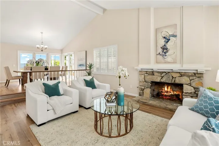 Living room with newer luxury vinyl flooring, fireplace, cathedral ceiling and view from dining room
