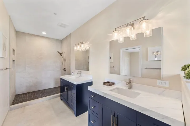 Luxurious primary bathroom featuring an oversized shower, dual sinks, and two spacious vanities.