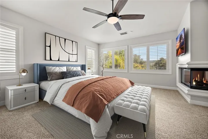 VIRTUALLY STAGED PRIMARY BEDROOM FEATURING A THREE SIDED FIREPLACE