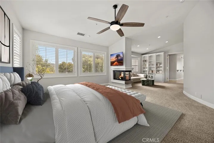 VIRTUALLY STAGED PRIMARY BEDROOM FEATURING A THREE SIDED FIREPLACE AND RETREAT