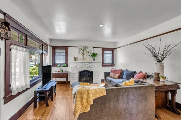 Living room with wood-burning fireplace, original window frames, and picture rail.
