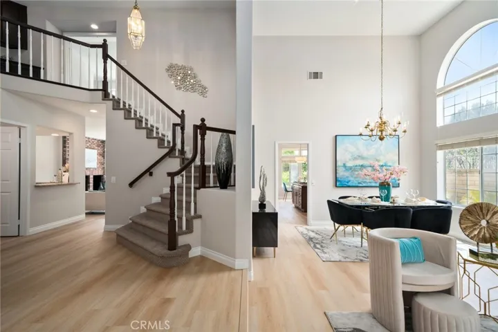 Formal living and dining room featuring soaring ceilings. The custom finished staircase adds architectural elegance.