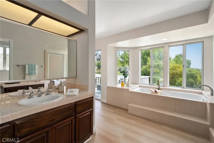 The primary en-suite bath includes dual vanities, a soaking tub, separate shower, with lots of natural light