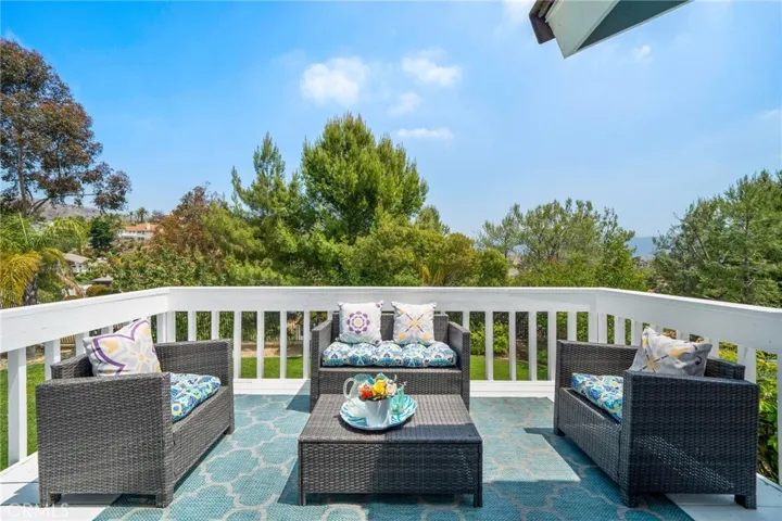 Balcony off of primary suite surrounded with mature landscaping and views of the spacious backyard.