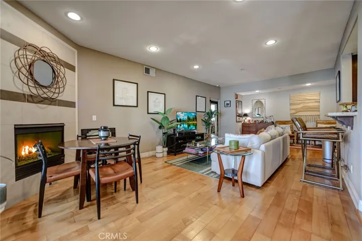 Living room with fireplace, breakfast bar that opens to kitchen, wood floors, recessed lights