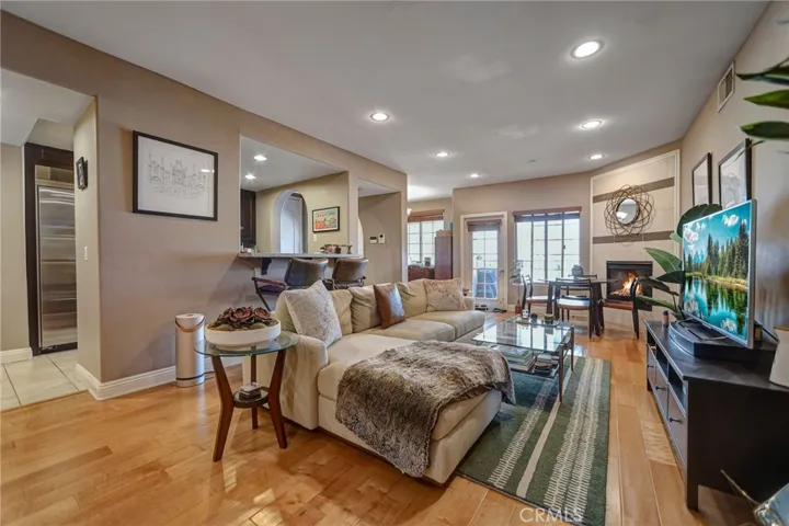 Living room w/ wood floors, fireplace and a cozy private balcony
