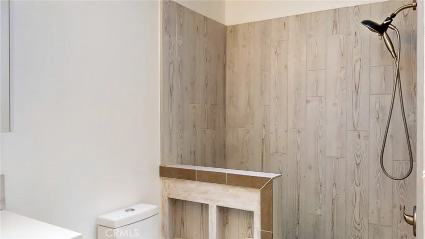 The walk-in shower features stone rock tile flooring.