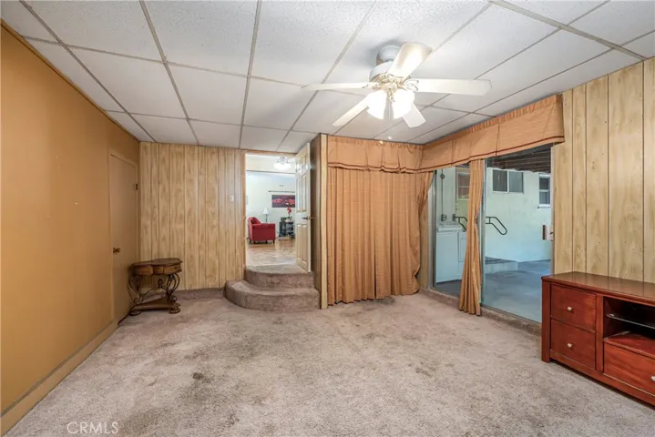 Den with shelving behind curtain and door to storage area