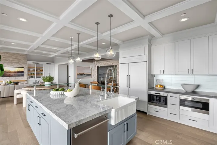 A built-in refrigerator displays cabinet-matched panels, while a built-in coffee station is joined by a six-burner Wolf range with griddle and double oven.