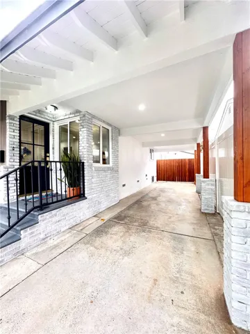 Driveway with covered carport (with huge storage space above) & garage behind the fence
