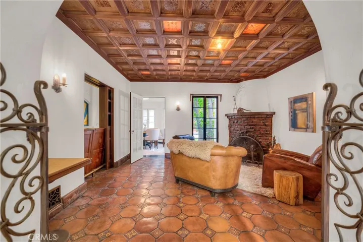 Wrought iron gates leading into the ceiling paneled den, on left is a hidden bar.