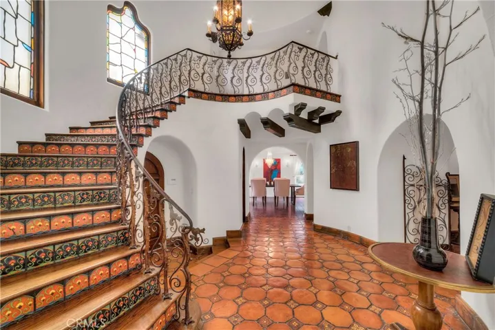 Entry, with custom pavers, tiled staircase, stained glass windows and custom wrought iron railing.