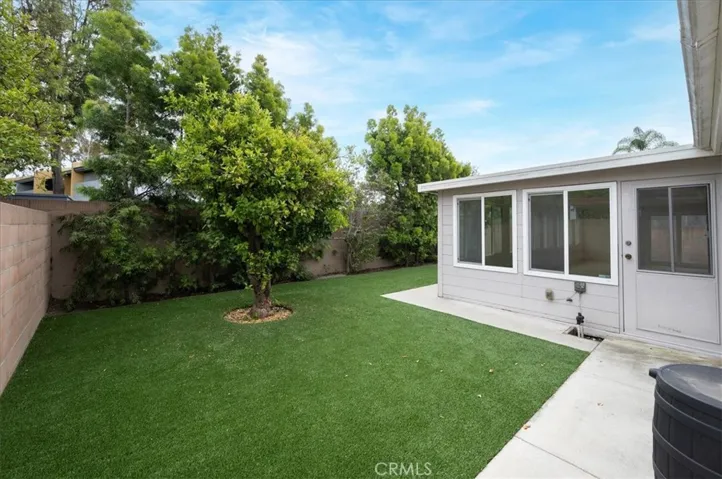 Backyard with artificial turf and fruit tree. Block walls surrounding property.