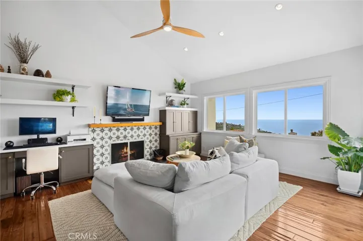 The kitchen opens to the main living area, which is anchored by a striking fireplace and framed by large windows that showcase sweeping views of the coastline, creating a warm and welcoming space to gather and unwind.